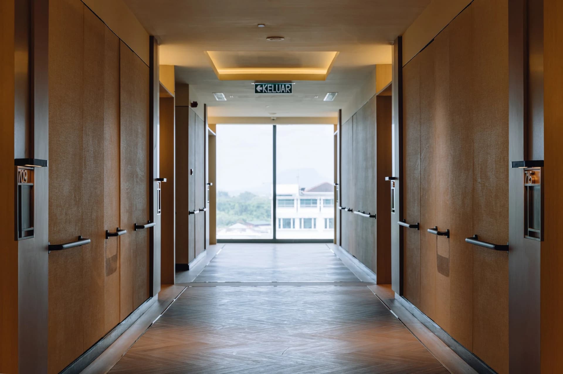 A wide corridor with grab rails, ending in a window